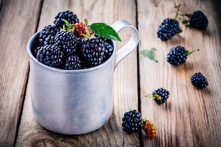 juicy fresh organic blackberries in old mug on a wooden backgroundの写真素材