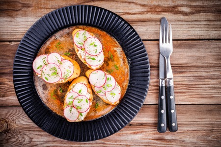 bruschetta with cream cheese, organic radish, onion and dill on wooden tableの写真素材