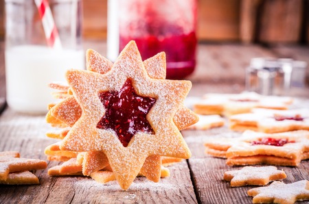 Christmas Linzer cookies with raspberry jam on a rustic wooden backgroundの写真素材