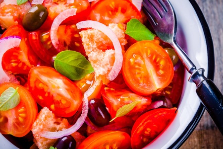 panzanella: Italian salad with tomatoes, ciabatta bread, olives, red onion and basil closeup on a wooden backgroundの写真素材