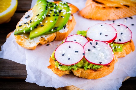 Bread with avocado, radish and sesame on wooden backgroundの写真素材