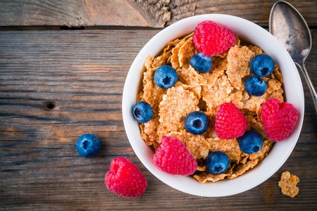 Healthy breakfast: whole grain cereals with raspberry and blueberry on wooden backgroundの写真素材
