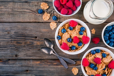 Healthy breakfast: whole grain cereals with raspberry and blueberry on wooden background