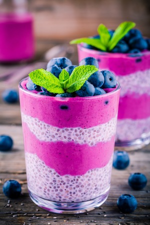 Blueberry smoothies with chia pudding in glass with fresh berries and mint on wooden backgroundの写真素材