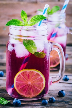 Blueberry ice mojito with lime and mint in mason jar on wooden backgroundの写真素材