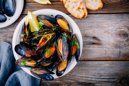 Delicious seafood mussels with with sauce and parsley.  Lemon and baguette . Clams in the shells.  Top view.の写真素材