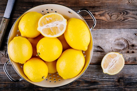 fresh organic lemons in a colander on a wooden background. view from aboveの写真素材