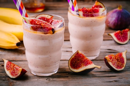 healthy breakfast smoothie with fresh figs, banana and honey in glasses on a wooden backgroundの写真素材
