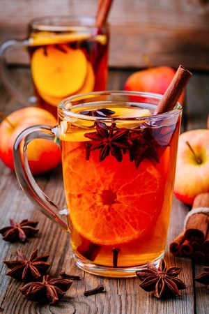 Hot mulled apple cider with cinnamon sticks, cloves and anise on wooden backgroundの写真素材