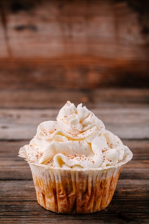 Pumpkin cupcakes decorated with cream cheese frosting on wooden backgroundの写真素材