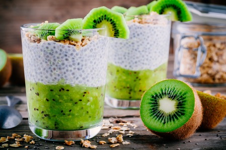 Healthy breakfast. chia pudding with kiwi and granola in glass on wooden backgroundの写真素材