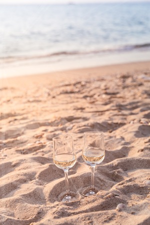 Two glasses of white wine on the beach at the summer sunny day. Sea on the backgroundの写真素材
