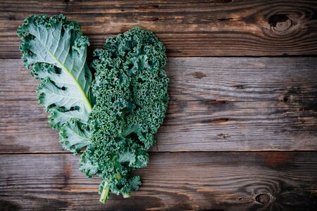 Fresh raw green superfood kale curly cabbage leaves on wooden backgroundの写真素材
