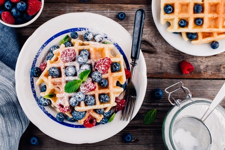 Fresh homemade belgian waffles with blueberries and raspberries for breakfast on wooden background.の写真素材