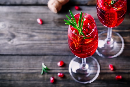 Pomegranate champagne mimosa cocktail with rosemary in glasses on wooden backgroundの写真素材
