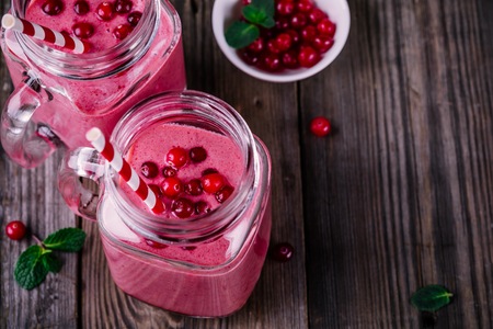 pink smoothie with wild cranberries in mason jar with mint and straw on rustic wooden backgroundの写真素材