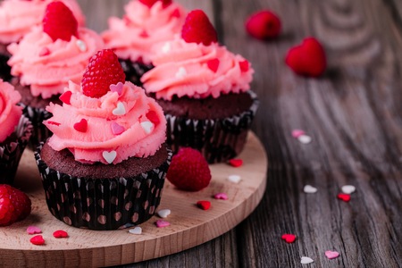 Chocolate cupcakes with pink cream, sugar hearts and fresh raspberries for St. Valentine's Dayの写真素材