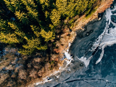 Aerial view of the winter snow covered forest and frozen lake from above captured with a drone in Finland.の写真素材
