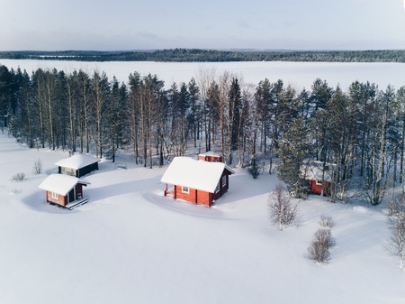 Scenic winter picture of a cottage near the lake and trees covered in snow. Finlandの写真素材