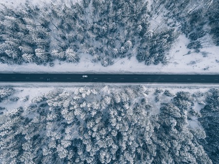 Country road going through the beautiful snow covered landscapes. Aerial view. Drone photography