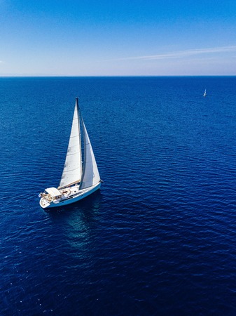 Aerial birds eye view from drone of white yacht in deep blue seaの写真素材