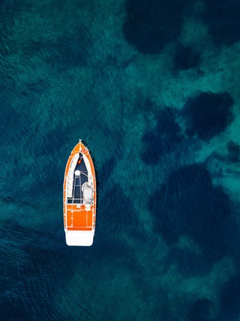 Red boat in deep blue water. Aerial view from drone