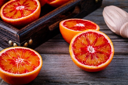 Sliced and whole ripe juicy Sicilian Blood oranges on wooden background. Selective focusの写真素材