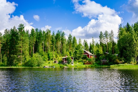 A traditional Finnish wooden cottage with a sauna and a barn on the lake shore. Summer landscape. Rural Finland.の写真素材