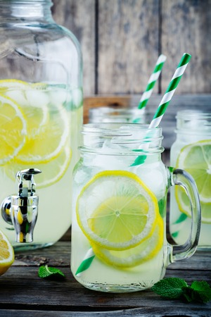 Homemade lemonade with mint, ice, and fresh lemon slices in mason jar on wooden backgroundの写真素材