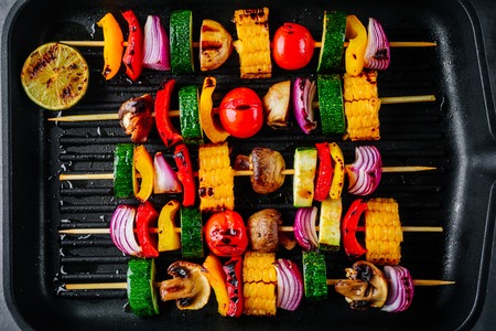 Grilled vegetable skewers with sweet corn, paprika, zucchini, onion, tomato and mushroom on a grill...