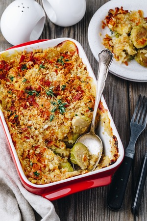 Baked brussel sprout gratin with a bacon and bread crumbs on wooden backgroundの写真素材