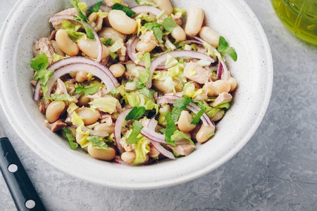 tuna salad with celery, white beans, red onion and parsley in white bowlの写真素材