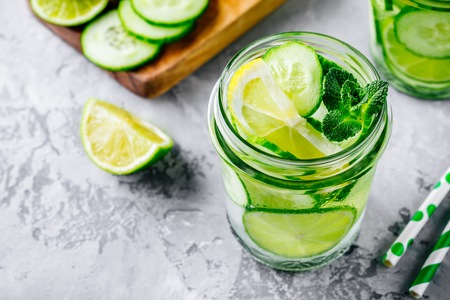 Infused detox water with  cucumber, lemon and lime. Refreshing ice cold summer cocktail or lemonade in glass jarの写真素材
