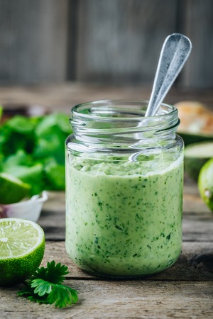 green salad dressing with avocado, lime and cilantro in a glass jar on a rustic backgroundの写真素材