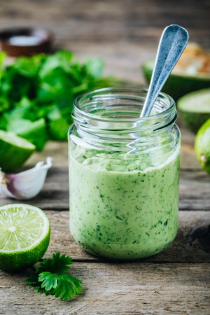 green salad dressing with avocado, lime and cilantro in a glass jar on a rustic backgroundの写真素材