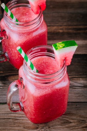 Watermelon smoothie in mason jars with mint on wooden rustic backgroundの写真素材