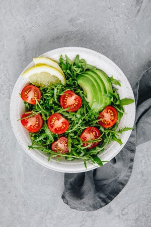 Green salad with leaves of arugula, tomatoes and avocado. Healthy summer lunchの写真素材