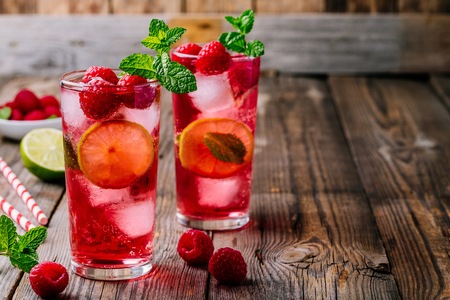Raspberry Mojito Lemonade with lime and fresh mint in glass on wooden background. Summer refreshing cocktail.の写真素材