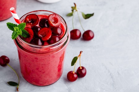Cherry smoothie in glass jars with mint leaves and fresh berriesの写真素材