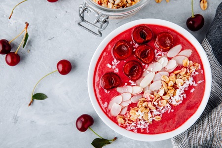 A healthy breakfast bowl. Red cherry smoothie with granola, almonds, coconut and fresh berriesの写真素材