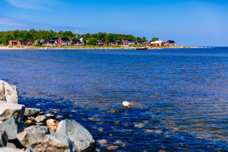 Red wooden houses on the lake or sea coast. Fishing village in rural Finlandの写真素材