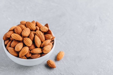 raw whole almond in bowl on gray background. Copy spaceの写真素材
