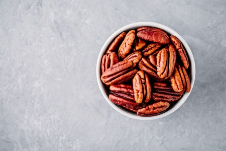 Raw pecan nuts in bowl on gray background. Top viewの写真素材