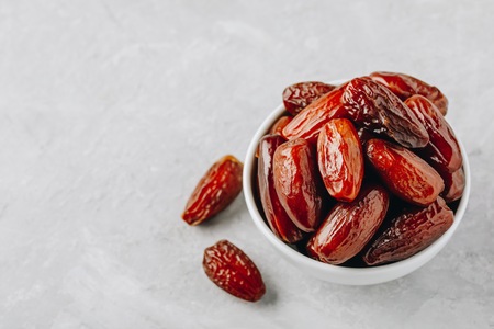 Dried dates in white bowl on grey stone backgroundの写真素材