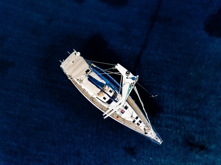 Aerial birds eye view from drone of yacht in deep blue sea in Greece.の写真素材