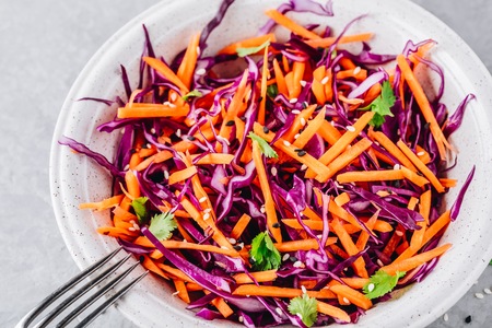 Red Cabbage and Carrot Slaw salad with cilantro and sesame seeds on stone backgroundの写真素材