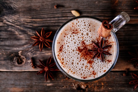 Homemade Chai Tea Latte with anise and cinnamon stick in glass mug on wooden rustic background. Top viewの写真素材