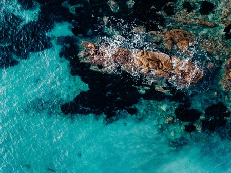 Aerial view of ocean waves and rocks. Blue and turquoise sea surfaceの写真素材