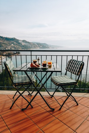 Delicious breakfast with coffee, pastry, and orange juice served on the balcony with sea view in Italy.の写真素材