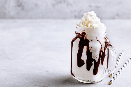 Frozen Hot Chocolate with whipped cream in mason jar on stone background